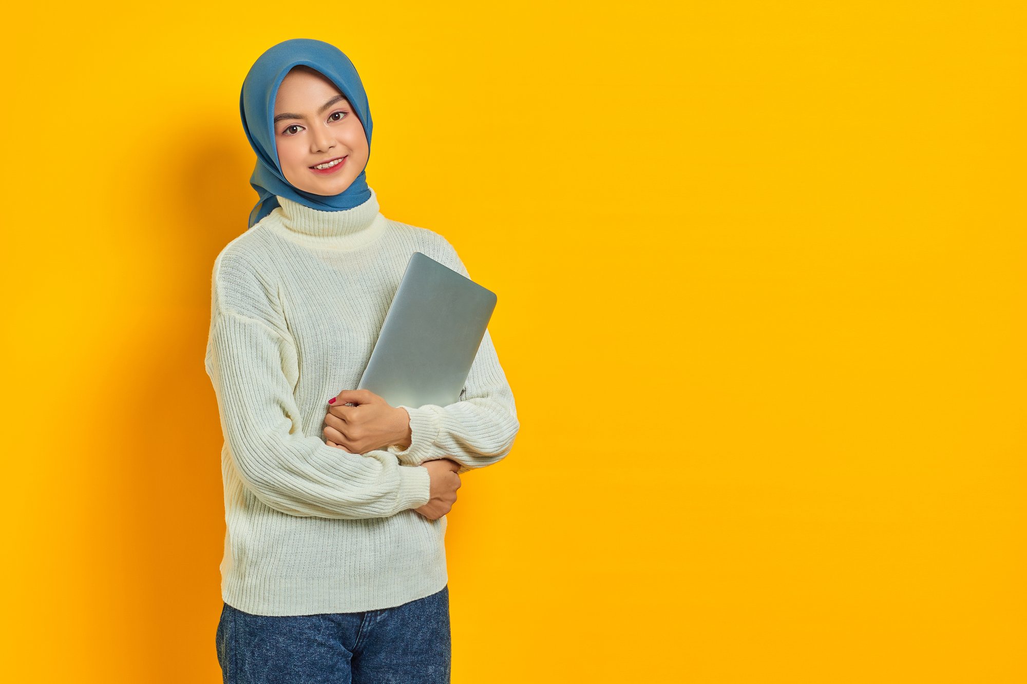 portrait-smiling-beautiful-asian-woman-white-sweater-hijab-holding-laptop-looking-camera-isolated-yellow-background-people-religious-lifestyle-concept